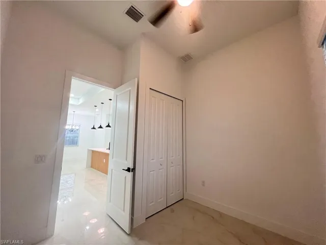 Unfurnished bedroom featuring a chandelier, a closet, and a ceiling fan