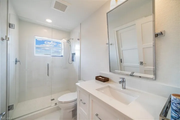 Bathroom featuring a shower with shower door, toilet, and vanity