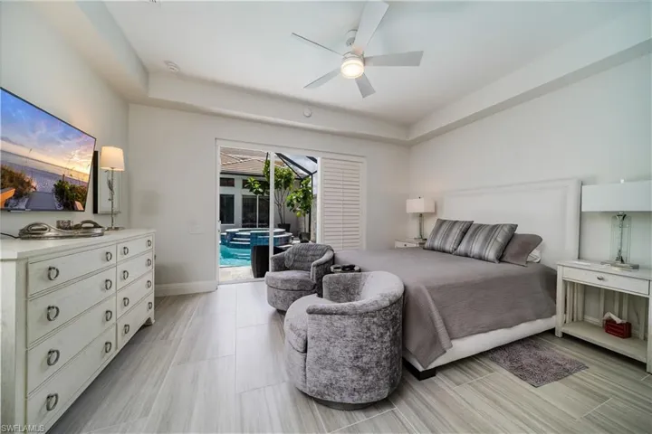 Bedroom with access to exterior courtyard, ceiling fan, and a raised ceiling