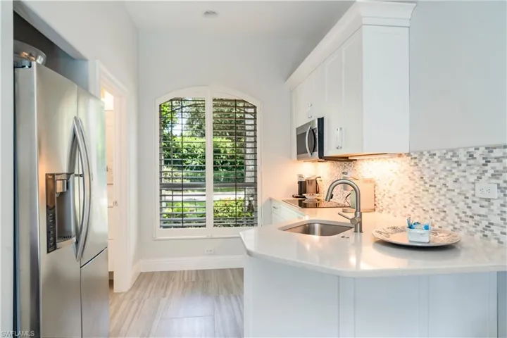 Kitchen #2 with white cabinetry, backsplash, kitchen peninsula, sink, and stainless steel appliances