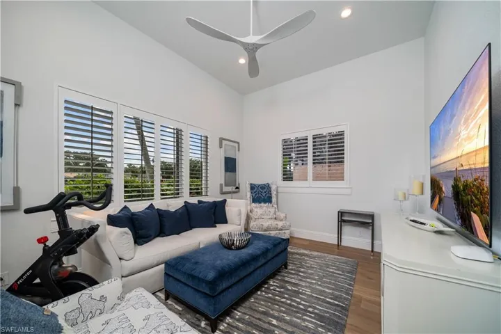1st floor den featuring high vaulted ceiling, ceiling fan, and hardwood flooring