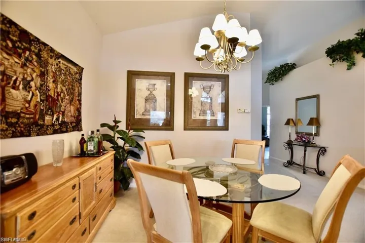 Carpeted dining room with a chandelier and lofted ceiling