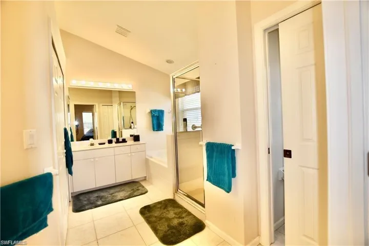 Bathroom with vanity, tile patterned flooring, lofted ceiling, and a wealth of natural light