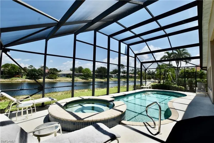 View of swimming pool with an in ground hot tub, a patio, a water view, and a lanai
