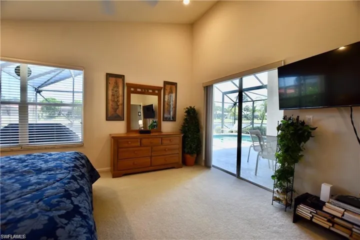 Bedroom with access to exterior, multiple windows, carpet flooring, and high vaulted ceiling