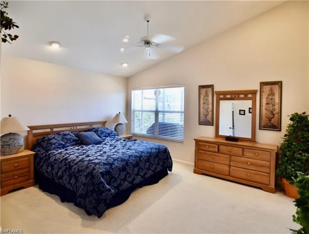 Carpeted bedroom with ceiling fan and vaulted ceiling