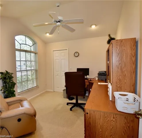 Carpeted office with vaulted ceiling and ceiling fan