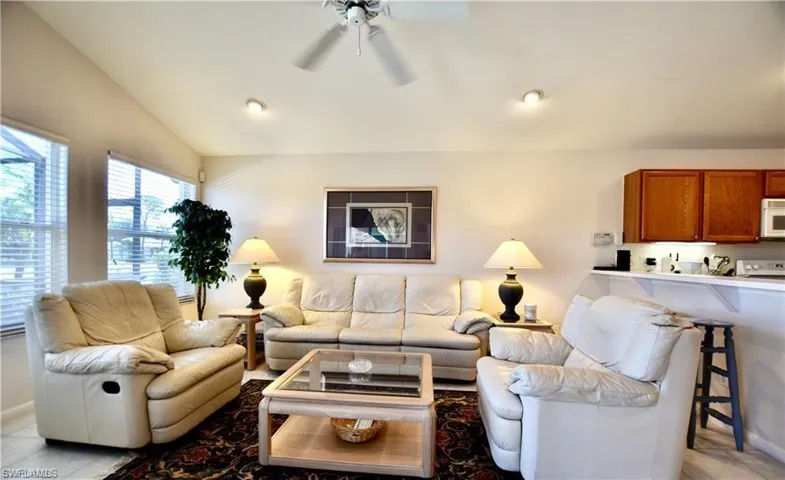Tiled living room with ceiling fan and vaulted ceiling