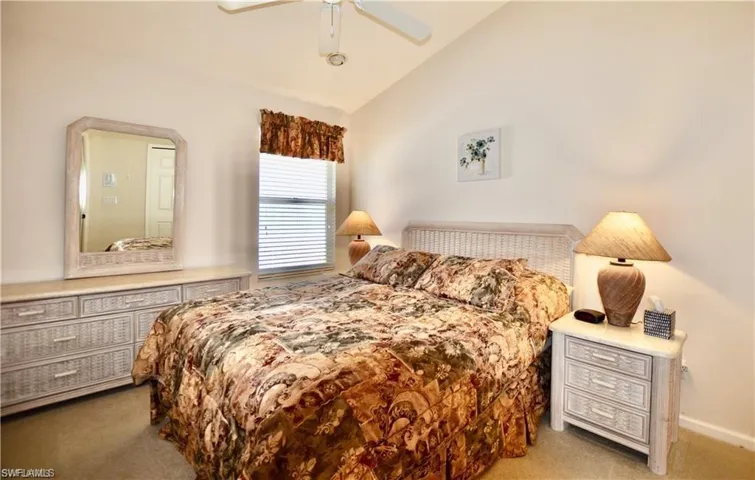 Carpeted bedroom with ceiling fan and lofted ceiling