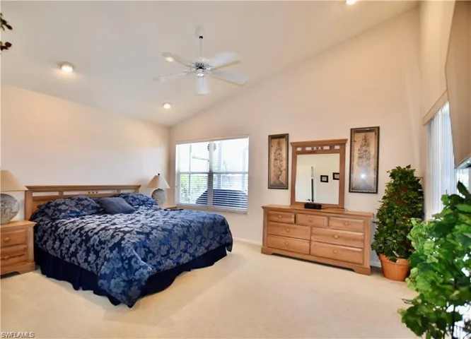 Bedroom with carpet flooring, ceiling fan, and high vaulted ceiling