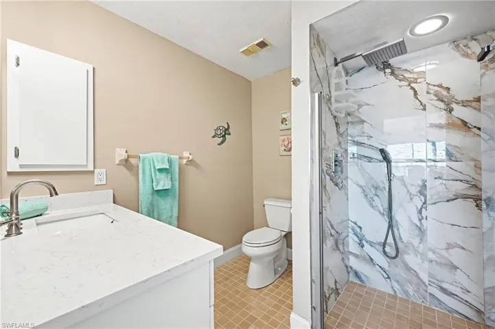Ensuite bath with updated counter toilet, tile, and shower with rain shower and shower wand.