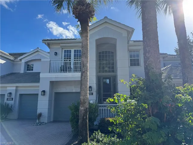 View of front facade with a balcony, a garage, stucco siding, and decorative driveway