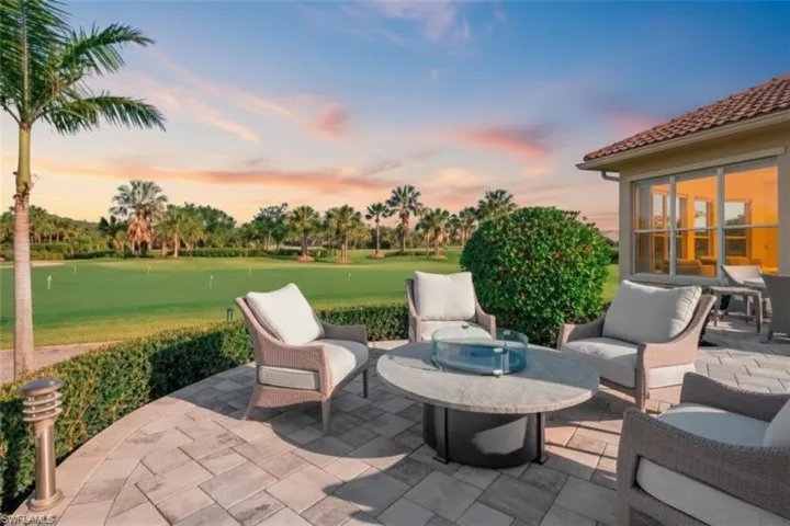 Paver patio with a fire pit, surrounded by manicured landscaping and golf course frontage