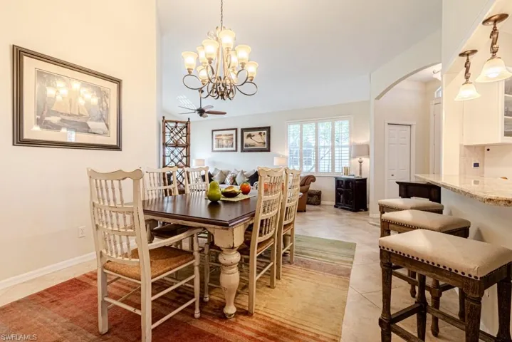 Tiled dining area featuring ceiling fan with notable chandelier