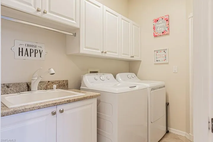 Washroom featuring sink, cabinets, washer and clothes dryer, and light tile patterned floors