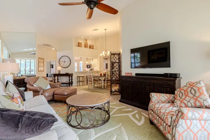 Living room featuring high vaulted ceiling and ceiling fan with notable chandelier