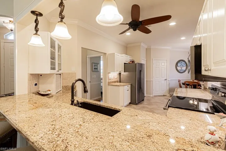 Kitchen featuring range, stainless steel refrigerator, tasteful backsplash, light stone counters, and sink
