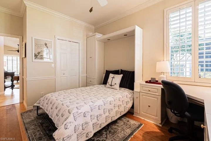 Bedroom with ornamental molding, light hardwood / wood-style flooring, a closet, and ceiling fan