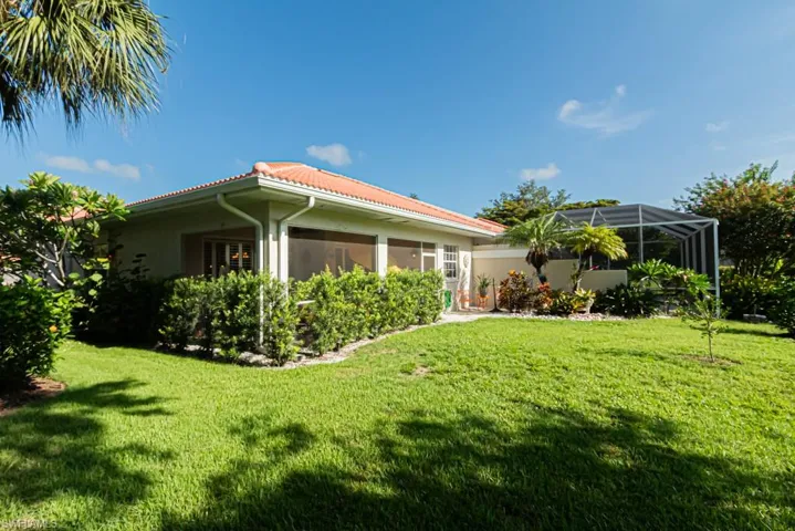 View of side of home featuring screened enclosure and a yard