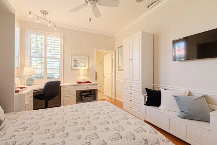 Bedroom with ceiling fan, light wood-type flooring, and crown molding