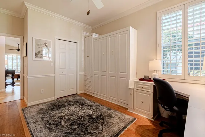Home office featuring crown molding, light wood-type flooring, and ceiling fan