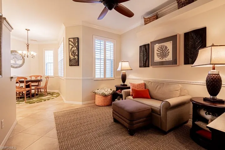 Tiled living room featuring ornamental molding and ceiling fan with notable chandelier