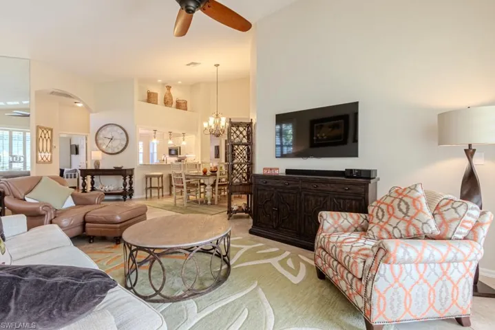 Living room with ceiling fan with notable chandelier and carpet