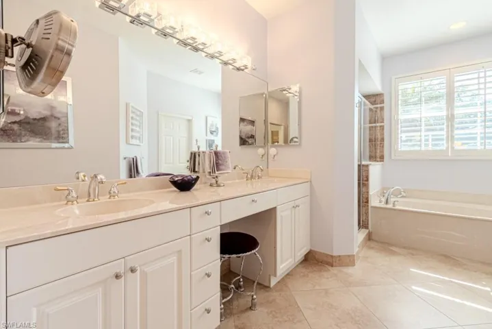 Bathroom featuring tile patterned floors, shower with separate bathtub, and dual bowl vanity