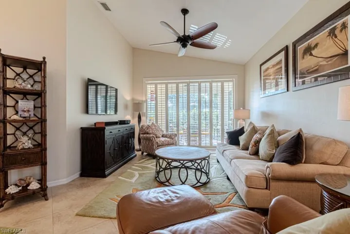 Living room featuring light tile patterned flooring, lofted ceiling, and ceiling fan