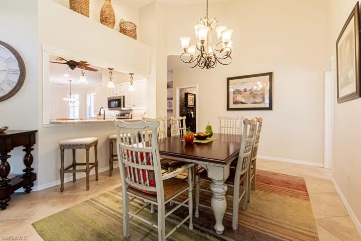 Tiled dining space featuring a high ceiling, sink, and ceiling fan with notable chandelier