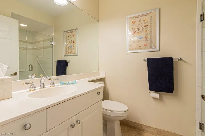 Bathroom featuring tile patterned flooring, a shower with door, toilet, and vanity
