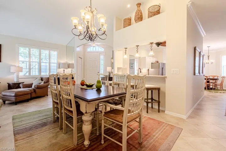 Dining area with an inviting chandelier, crown molding, a towering ceiling, and light tile patterned floors