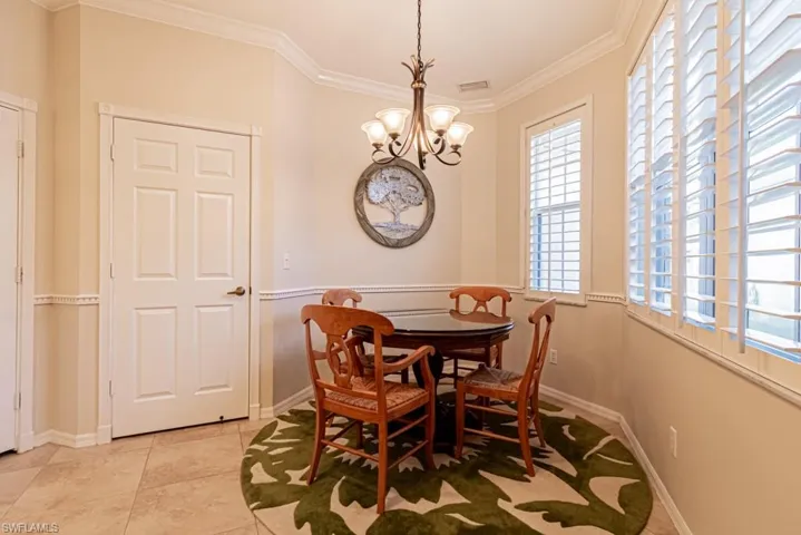 Dining room with light tile patterned flooring, crown molding, and an inviting chandelier
