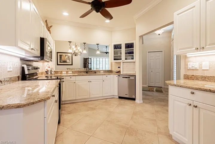 Kitchen with white cabinets, ceiling fan with notable chandelier, tasteful backsplash, and stainless steel appliances