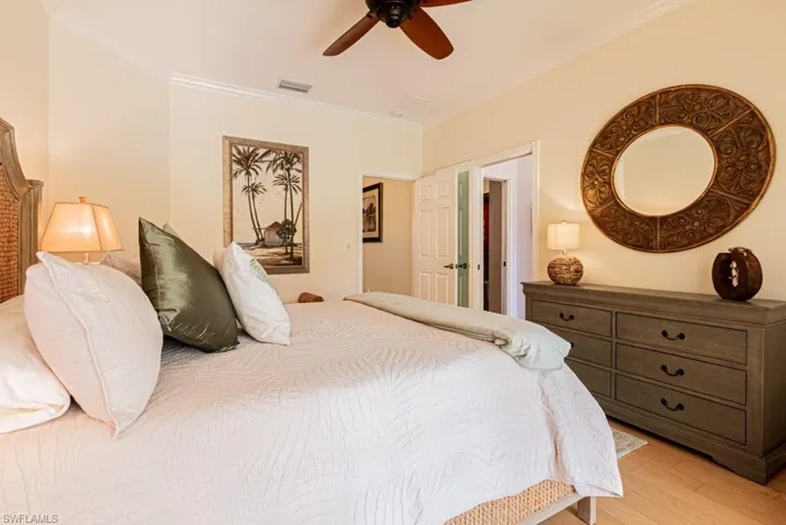 Bedroom with ceiling fan, wood-type flooring, and ornamental molding