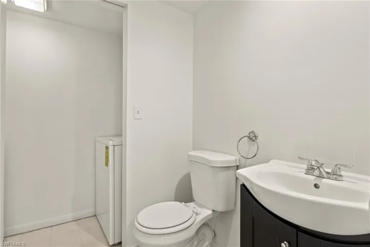 Contemporary bathroom featuring a white toilet, black vanity with an integrated white sink, and chrome fixtures