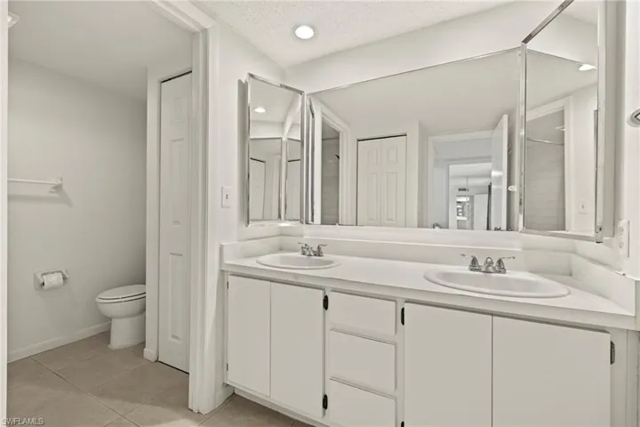 Bathroom featuring a dual vanity with integrated sinks, white cabinetry, and a mirrored medicine cabinet
