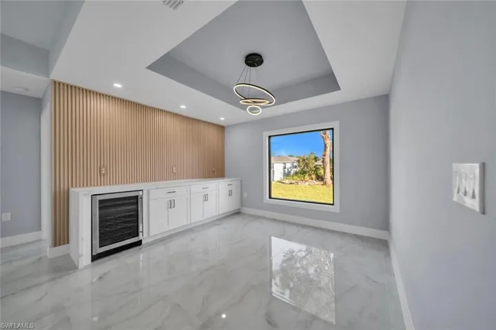 Modern beverage bar featuring an integrated wine refrigerator, wood-slat accent wall, and recessed lighting