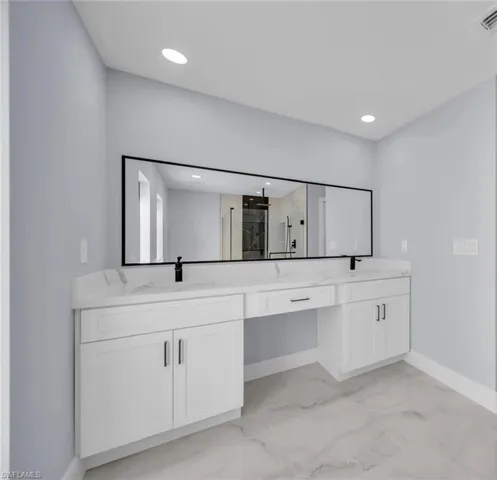 Spacious bathroom featuring a dual vanity with white cabinetry, a light-toned countertop, and undermount sinks with matte black fixtures