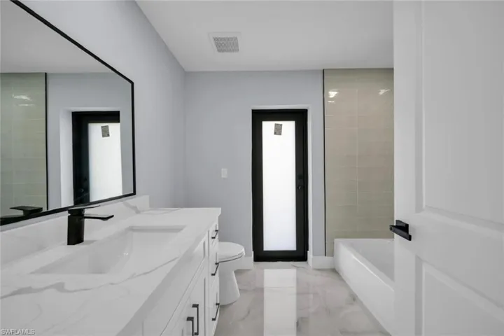 Bathroom featuring a dual-sink vanity with white countertops, undermount sinks, and matte black fixtures
