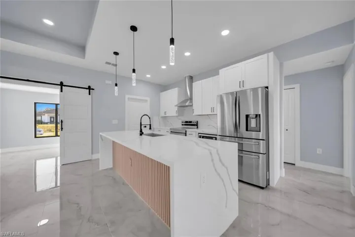 Contemporary kitchen featuring an oversized island with waterfall countertop, integrated sink, and an accent panel
