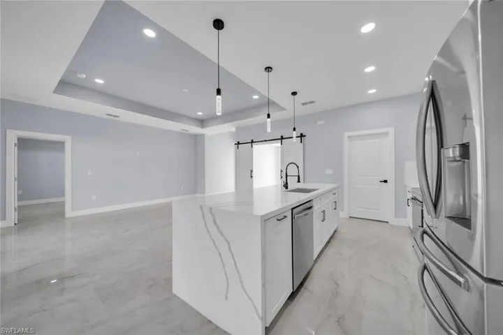 Kitchen island with waterfall countertop, integrated sink, and dishwasher