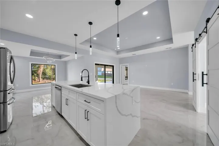 Spacious kitchen with a large island featuring a waterfall-edge countertop and undermount sink