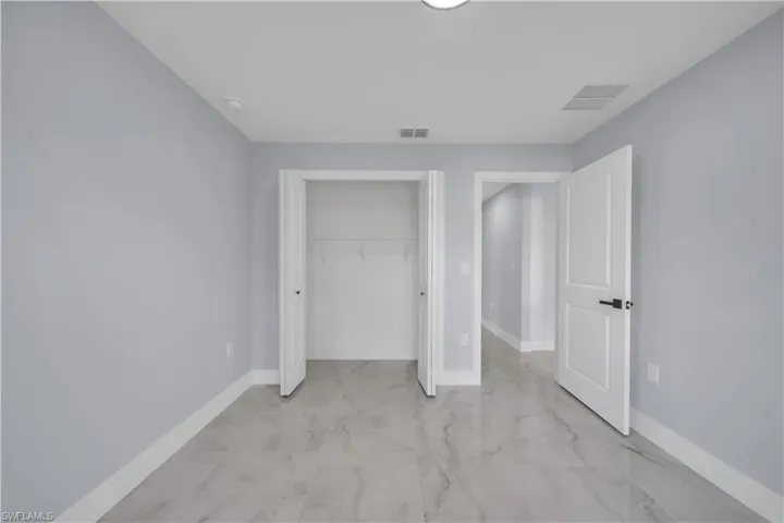 Spacious room featuring light gray walls, large format tile flooring, and white baseboards