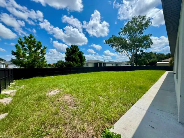 Expansive grassy yard with a black privacy fence