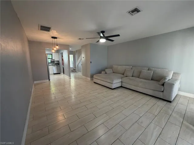Living area with stairway, a ceiling fan, and wood finish floors