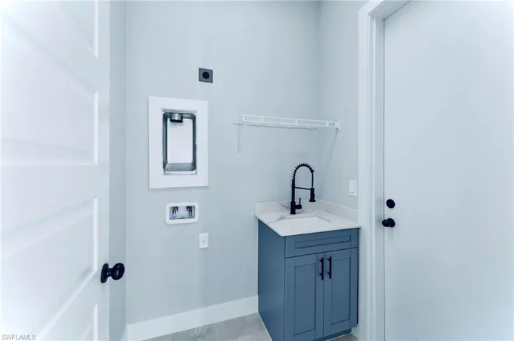 Laundry area with washer hookup, cabinet space, and light tile patterned flooring