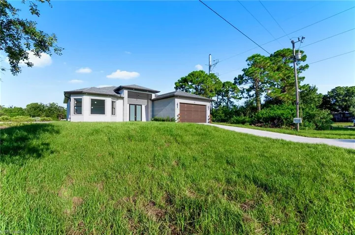 Prairie-style house featuring concrete driveway, a garage, stucco siding, and a front lawn