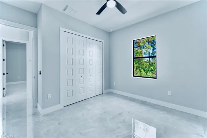 Unfurnished bedroom featuring a closet, ceiling fan, and light marble finish floors