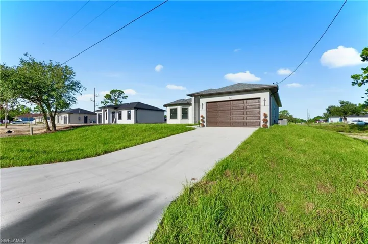 Prairie-style house featuring an attached garage, driveway, a front yard, and stucco siding